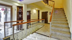 A hotel lobby with a marble staircase, a wooden railing, and decorative metal railings.