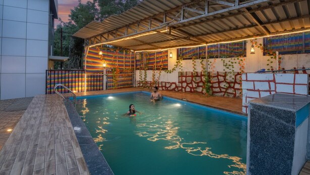 An indoor swimming pool with a tiled deck, a covered area with colorful wall decorations, and a stone structure.