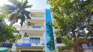 Un hotel de varios pisos con balcones, una franja vertical azul en la fachada y vegetación circundante.