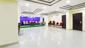 A spacious hall with a stage, rows of chairs, and a podium. - Fabhotel L Grand (Hyderabad)