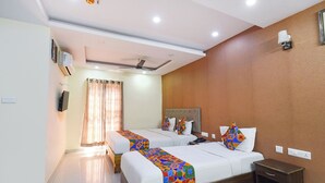 A hotel room with two beds, a wooden headboard, a bedside table, a nightstand, and a ceiling fan. - Fabhotel L Grand (Hyderabad)