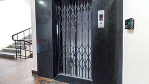 A black metal gate with a keypad and a digital display, a staircase, and a marble floor. - Fabhotel L Grand (Hyderabad)