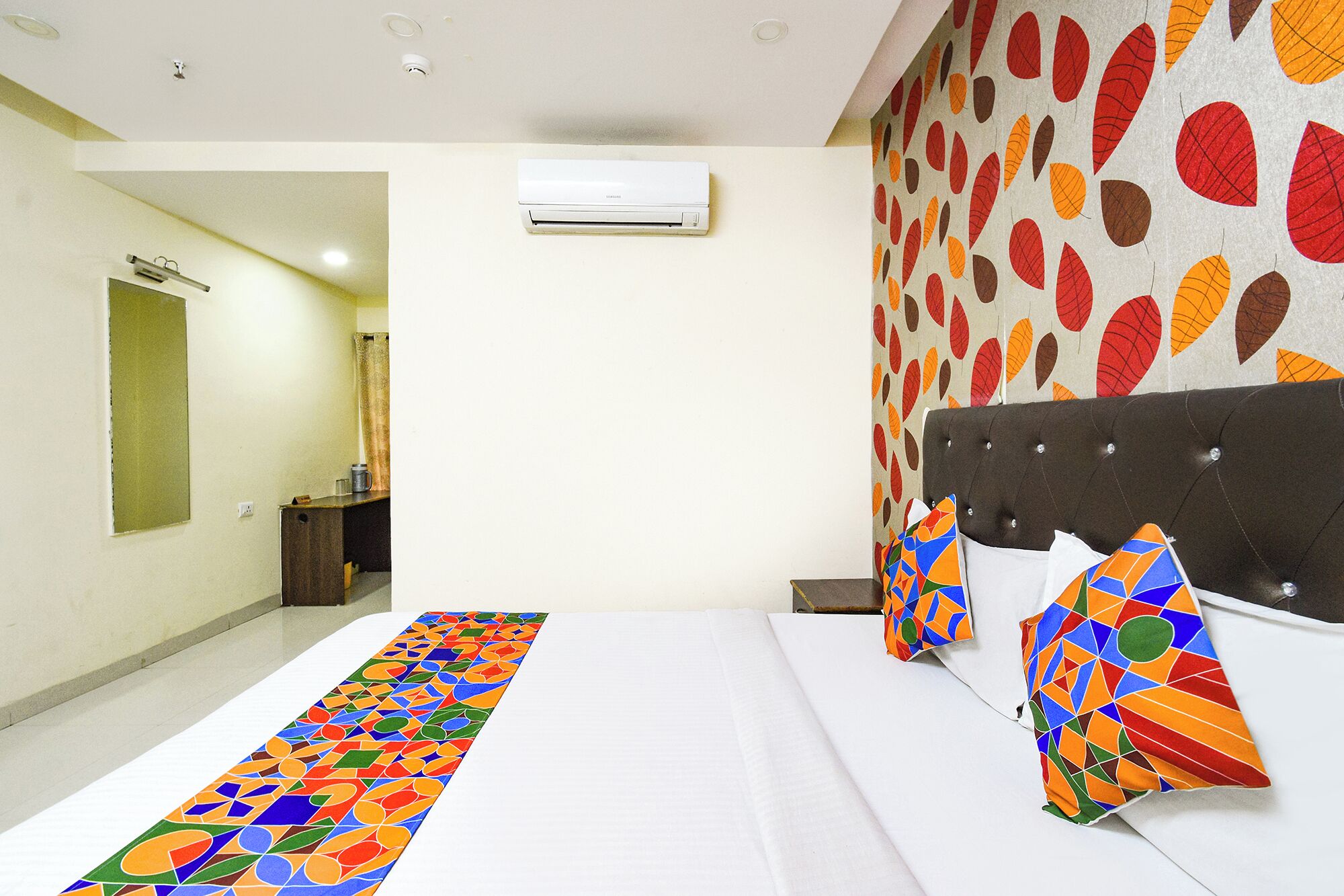 A hotel room with a bed, a bathroom, and a wall with a leaf pattern.