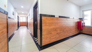 Un pasillo con paneles de madera y suelo de baldosas que conduce a una puerta con un extintor en la pared.