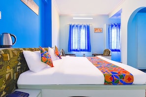 A hotel room with a large bed, a coffee maker, and a view of the outside through a window. - Fabexpress Anuja (Jaipur)