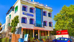 Um hotel de vários andares com entrada destacada, varandas e uma placa com a inscrição 'Hotel Anuja'.