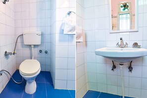 A bathroom with a toilet, a sink, and a mirror. - Fabexpress Anuja (Jaipur)