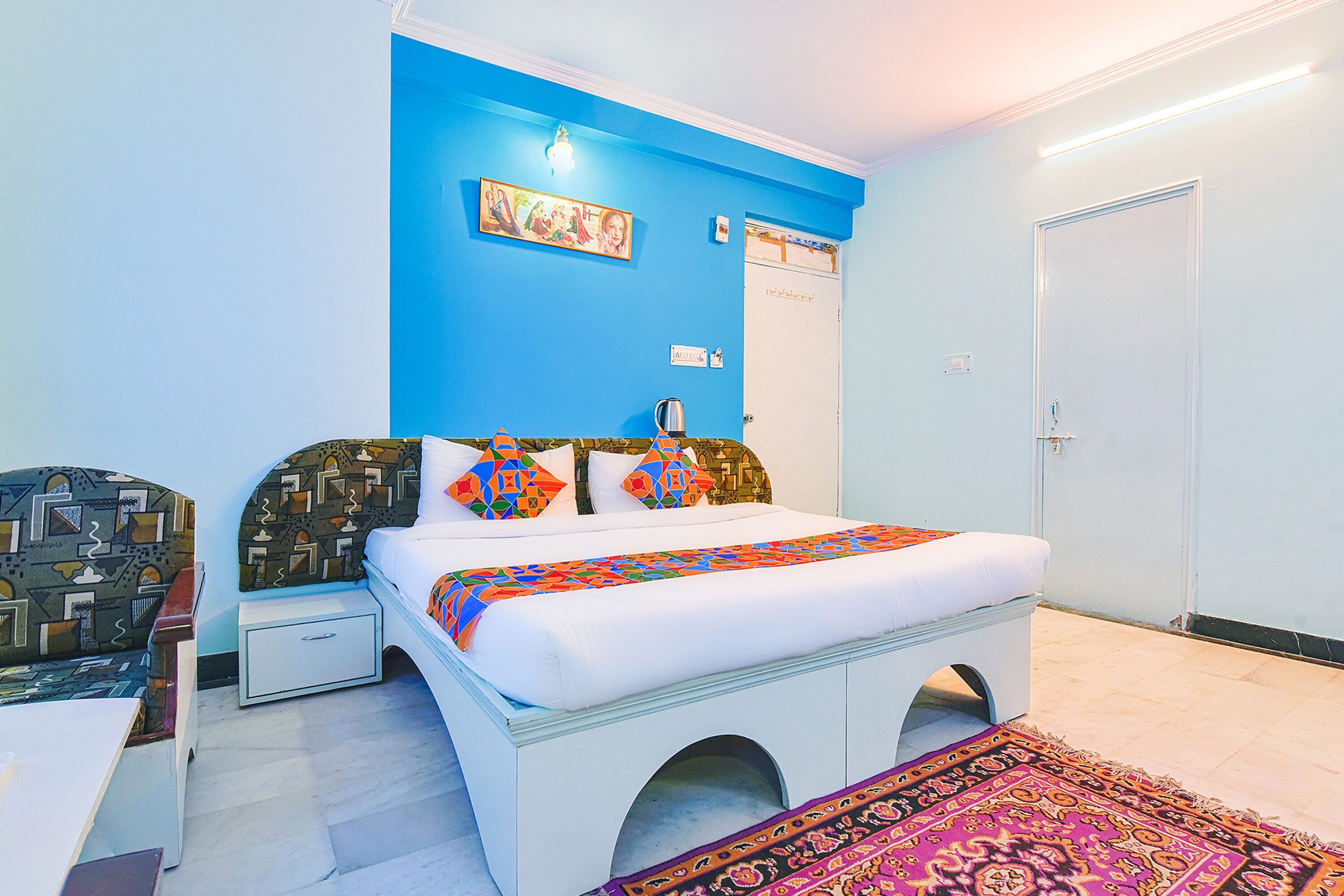 A bedroom with a bed, nightstand, and a wall-mounted shelf.