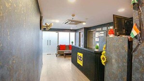 A reception area with a sofa, a desk, and an air conditioning unit. - FabHotel Blusky (New Delhi)