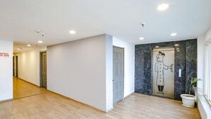 A hallway with wooden flooring, white walls, and a door with a marble accent. - FabHotel Blusky (New Delhi)