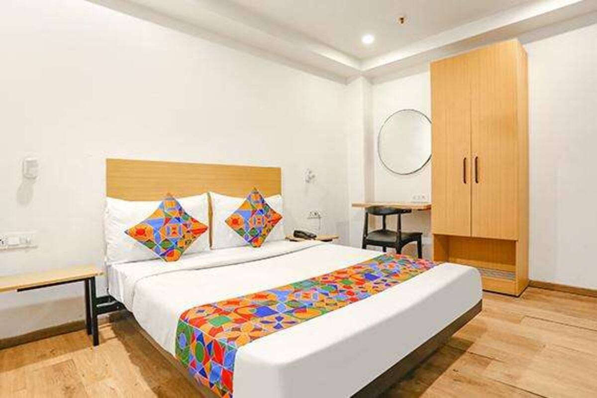 A bedroom with a bed, a wooden wardrobe, a desk, and a chair.