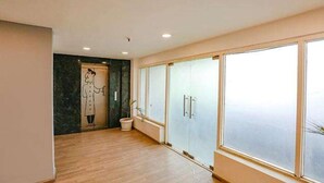 A spacious hallway with a large window, a marble wall with a mural, and a door with a handle. - FabHotel Blusky (New Delhi)