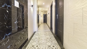 A hallway with marble walls, patterned floor tiles, and doors leading to rooms. - FabHotel Prime AV Royale (Dehradun)