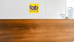 A wooden reception desk with a logo for Fab Hotels on the wall. - Fabhotel Dr Greens (Indore)