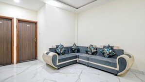 A modern living room with a sectional sofa, a wooden door, and a tiled floor. - Fabhotel Dr Greens (Indore)