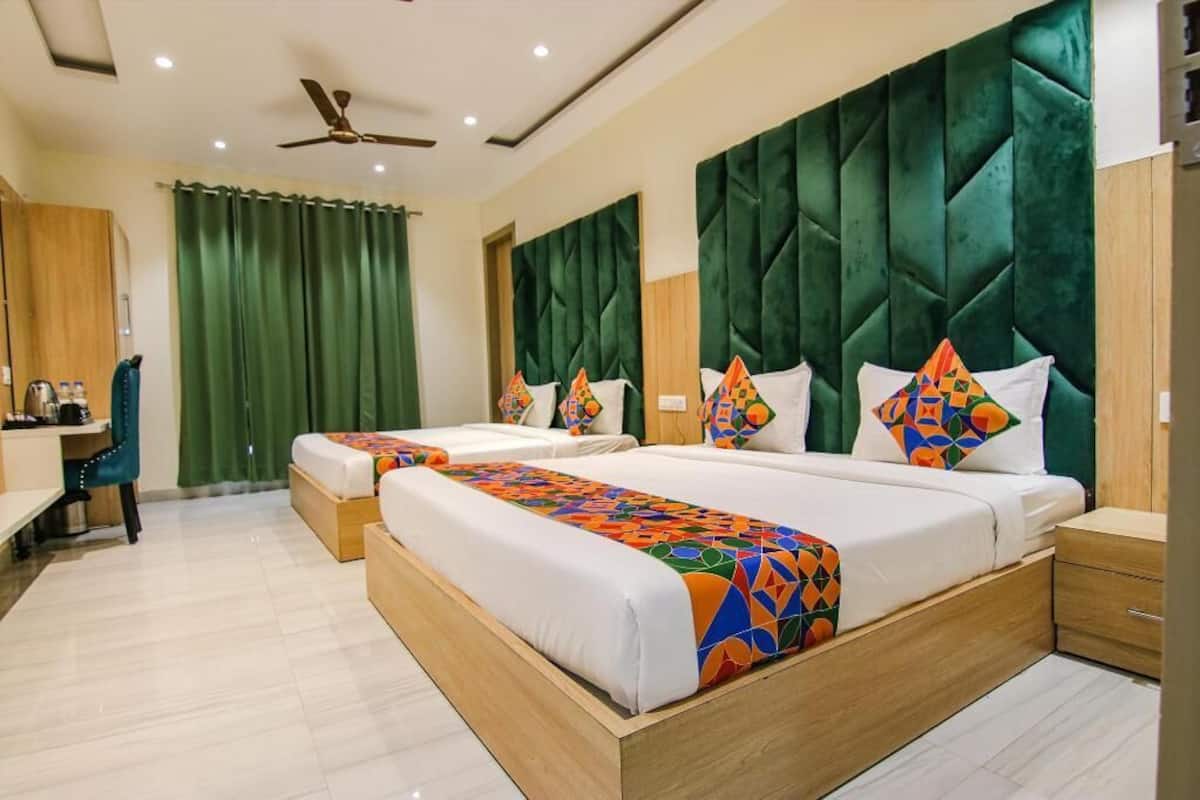 A hotel room with two beds, a desk, a chair, and a wardrobe.