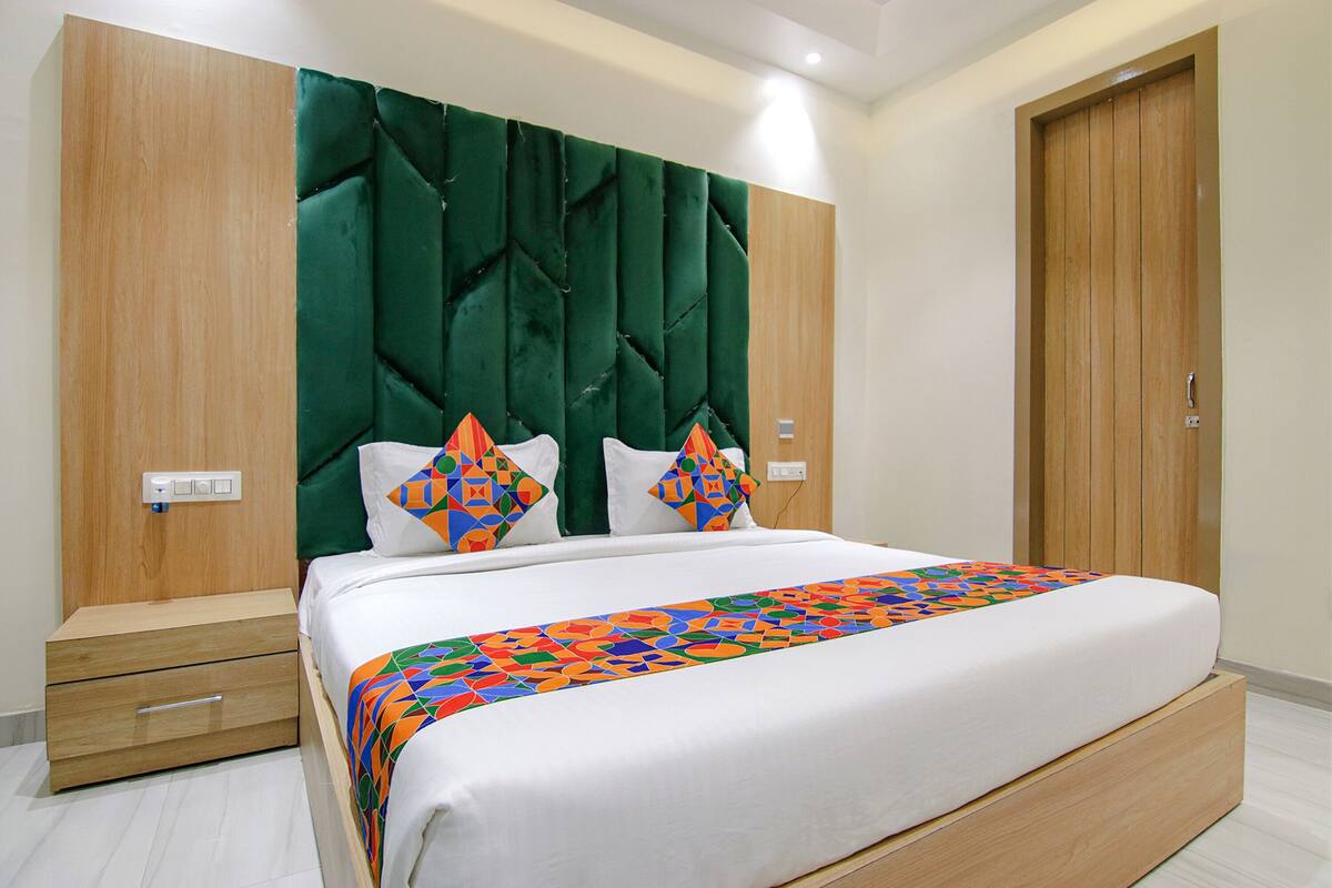 A bedroom with a bed, a wooden nightstand, a green upholstered headboard, and a wooden wardrobe.