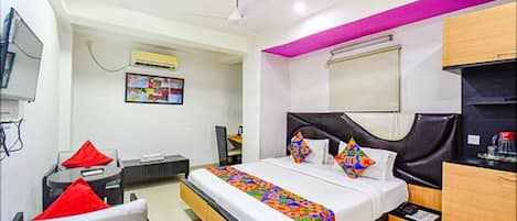 A hotel room with a bed, a desk, a chair, a TV, and a ceiling fan.