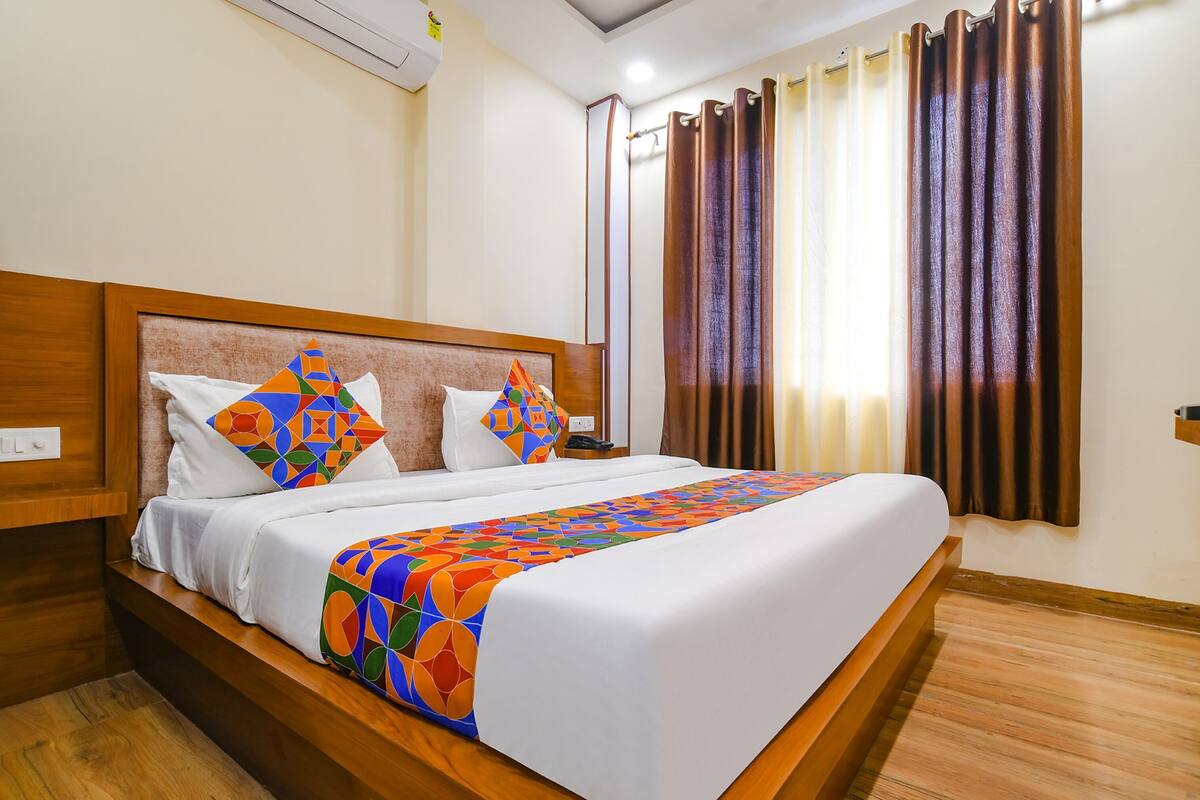 Una habitación de hotel con una cama grande, cabecera de madera y una colcha colorida.