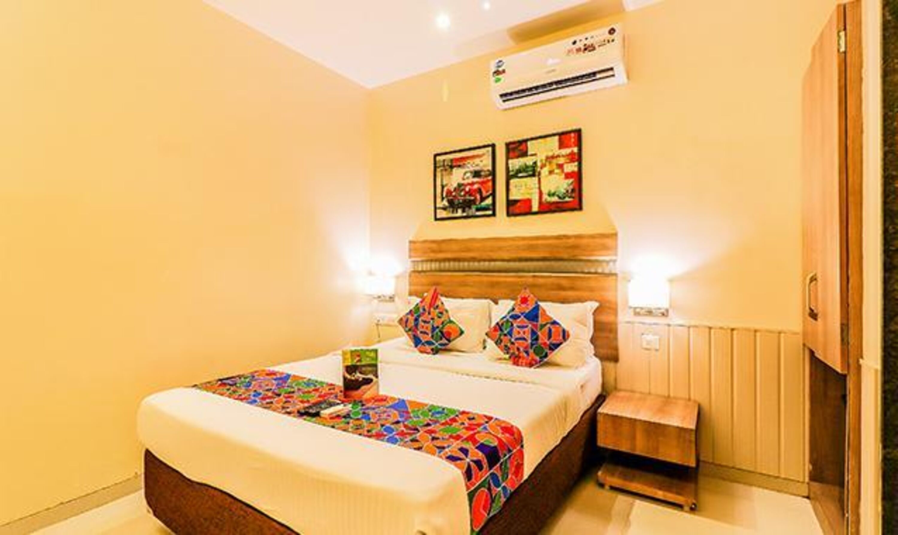 Una habitación de hotel con una cama, una mesita de noche y un aire acondicionado instalado en la pared.