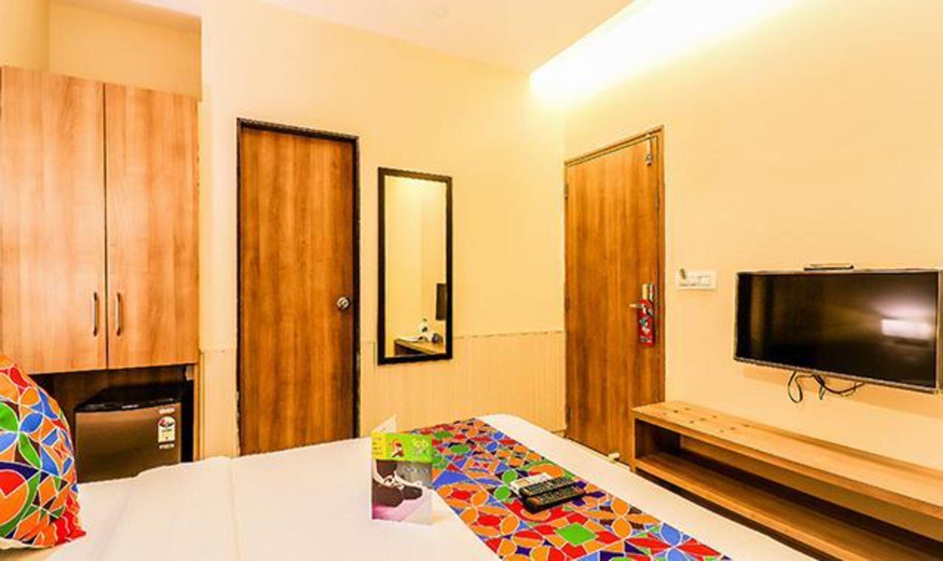 Une chambre d’hôtel avec un lit, une télévision, une armoire et un miroir.