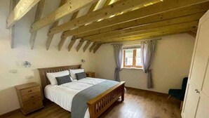 A bedroom with a wooden bed, a nightstand, a window with curtains, and a wardrobe. - Charming Norfolk Barn Conversion in Barnham Broom (Norwich)