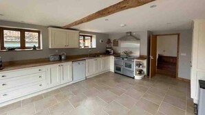 A spacious kitchen with white cabinets, a built-in oven, and a large window. - Charming Norfolk Barn Conversion in Barnham Broom (Norwich)