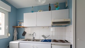 A compact kitchen with white cabinets, a stainless steel sink, and a built-in stove. - Quiet T2 Apartment in Arcachon with Private Parking, Terrace, and Close to Beach and Shops (Arcachon)