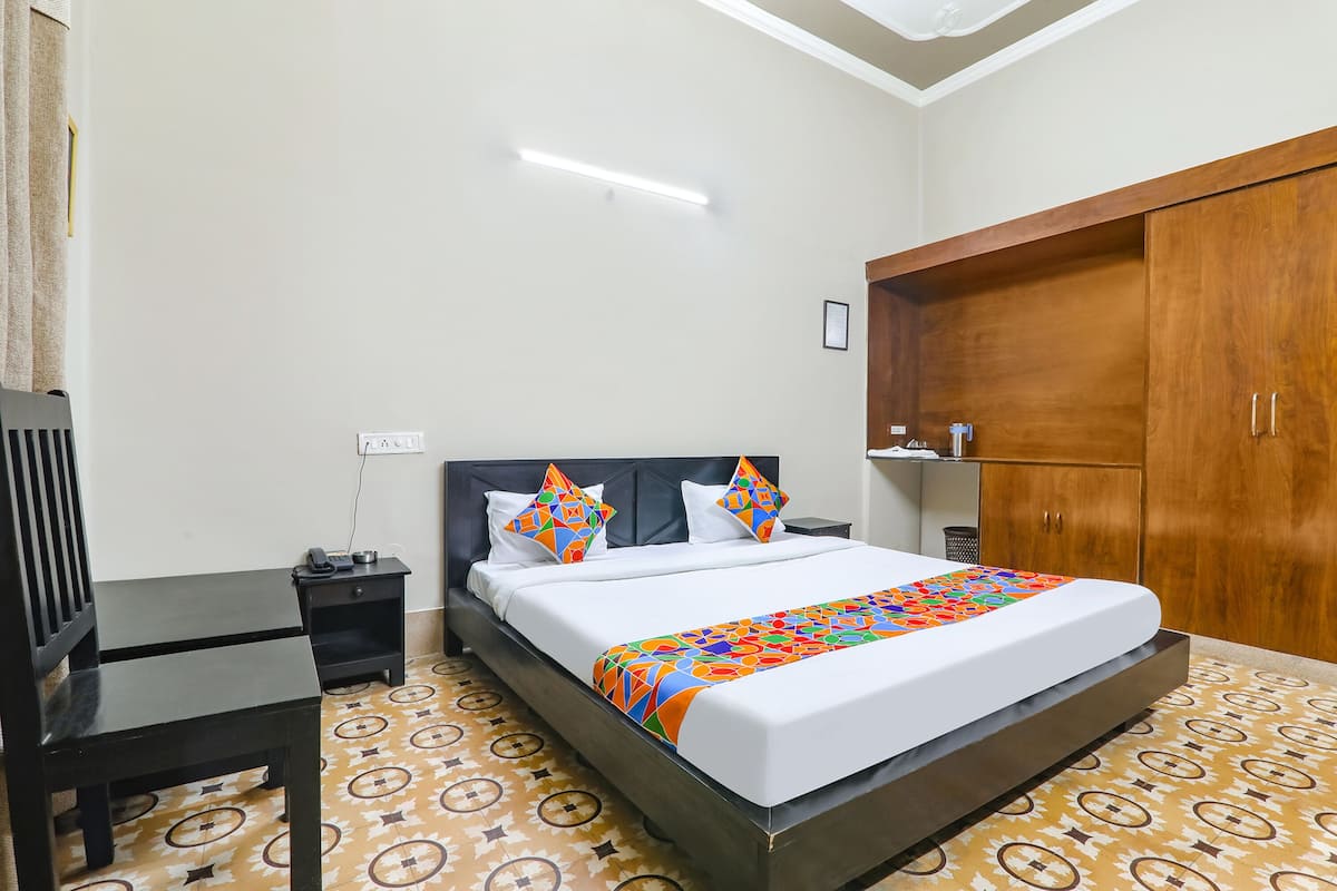 A neatly arranged hotel room with a bed, bedside table, and wardrobe.