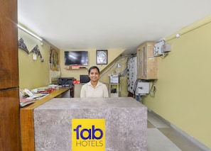 A reception desk with a logo for Fab Hotels, a television mounted on the wall, and various electronic equipment on the wall. - Fabhotel Harmony (Prayagraj)