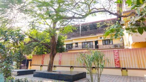 A courtyard with a tree, a bench, and a building with balconies. - Fabhotel Harmony (Prayagraj)