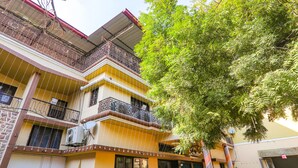 A multi-story building with balconies, a tree in front, and a building with a yellow facade. - Fabhotel Harmony (Prayagraj)