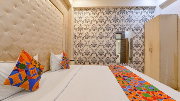 A hotel room with a tufted headboard, patterned wallpaper, a long bed with a colorful runner, and a wardrobe. - Fabhotel Triveni (Prayagraj)