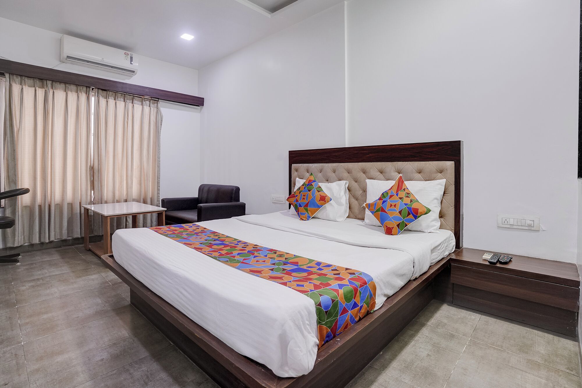 Una habitación de hotel con una cama, una silla, un escritorio y una mesita de noche.