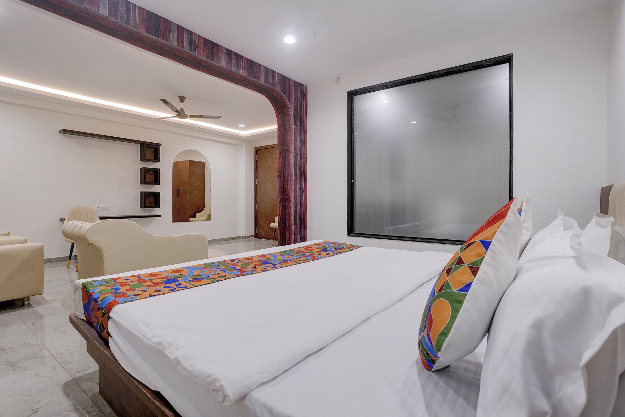 A hotel room with a bed, a chair, a desk, and a wardrobe.