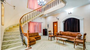 Amplia sala de estar con una escalera curva, un conjunto de sofás, una mesa de centro y una chimenea.