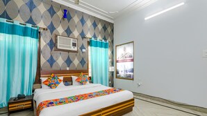 Habitación de hotel con una cama grande, cortinas, aire acondicionado instalado en la pared y un cuadro enmarcado.