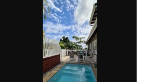 A rectangular swimming pool with a white fence and a red wall on one side. - Luxury villas with private pools in the countryside (Le Marin)