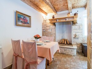 Un comedor con pared de piedra, vigas de madera y una mesa preparada para dos.