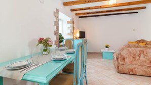 Un comedor con una mesa lista para dos, un sofá y un televisor sobre un mueble.