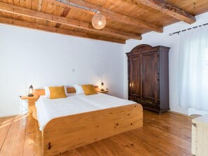 Una cama de madera en una habitación con techo alto y un armario de madera oscura.
