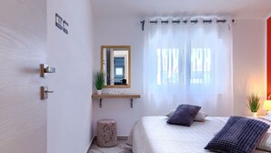 A bedroom with a bed, a bedside table, a mirror, and a window with curtains. - Dragica by Interhome (Pula)