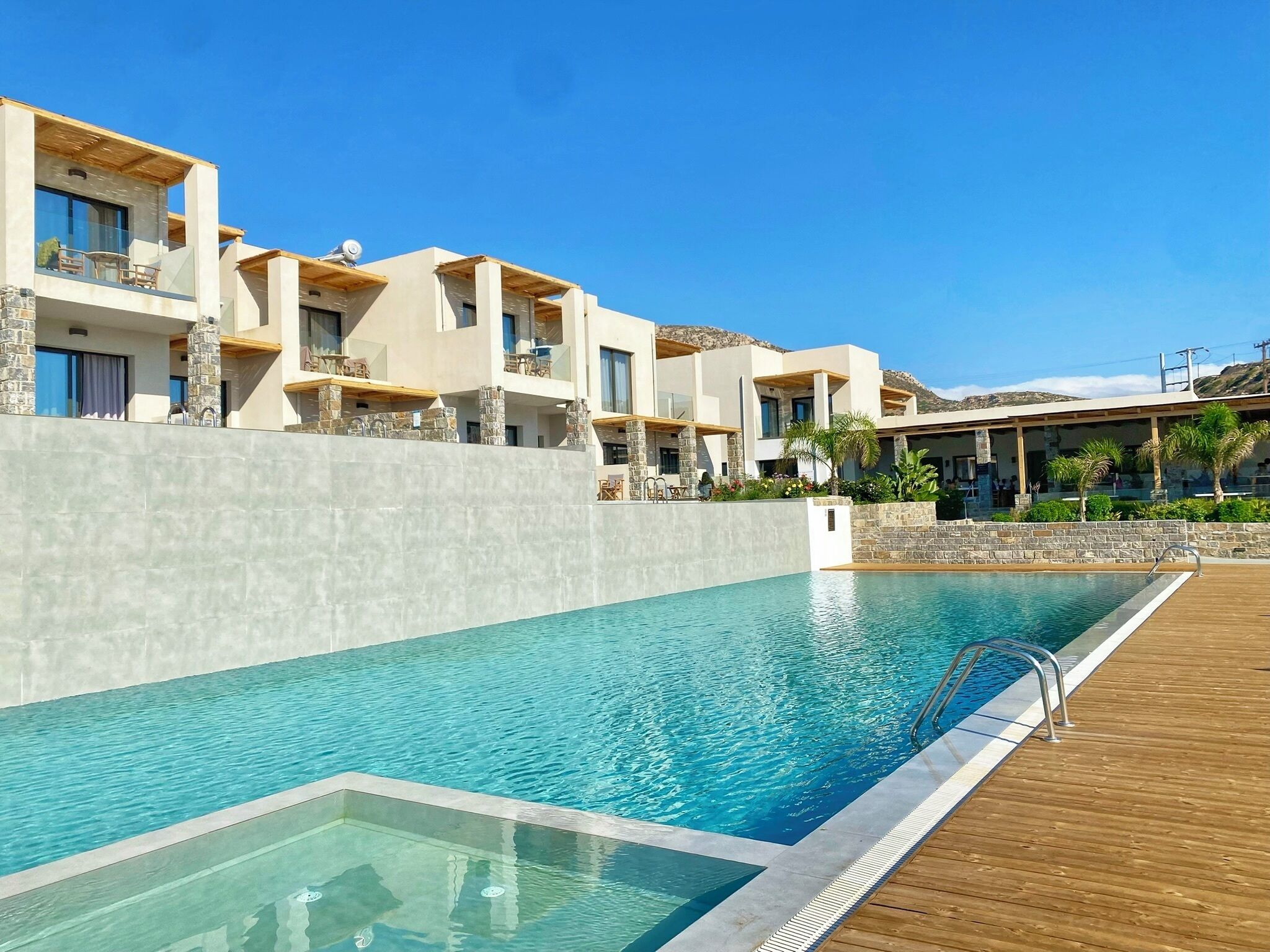 A modern hotel with a swimming pool, stone pillars, and a wooden deck.