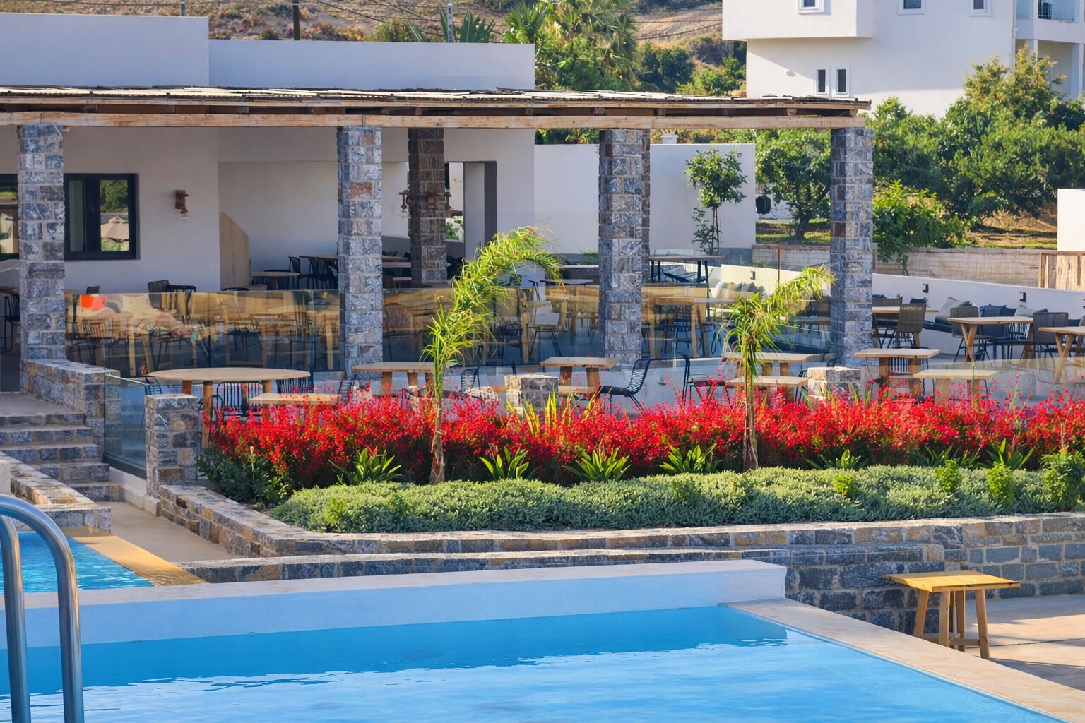 A poolside area with stone pillars, outdoor seating, and a pool.