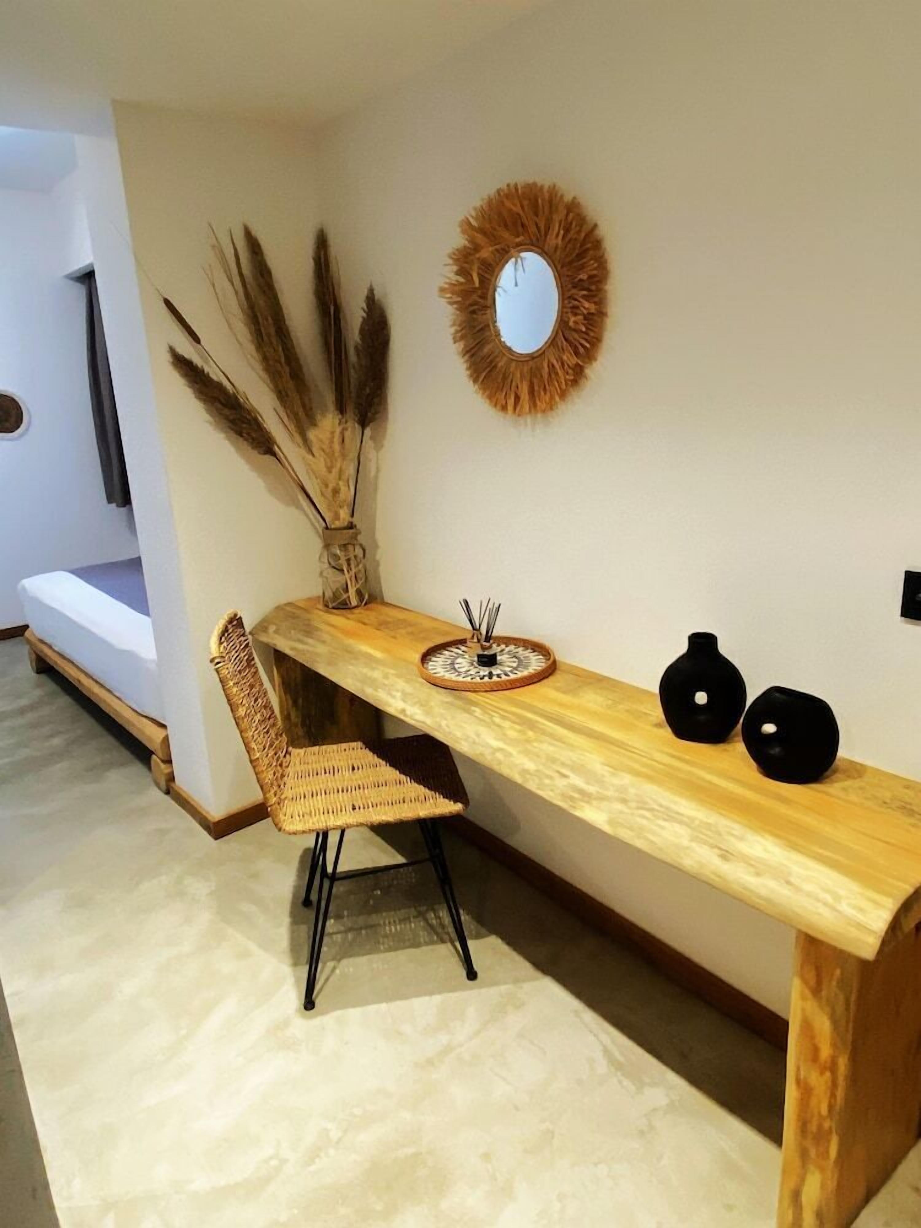 Un comedor con una mesa de madera, dos jarrones negros y un espejo en la pared.