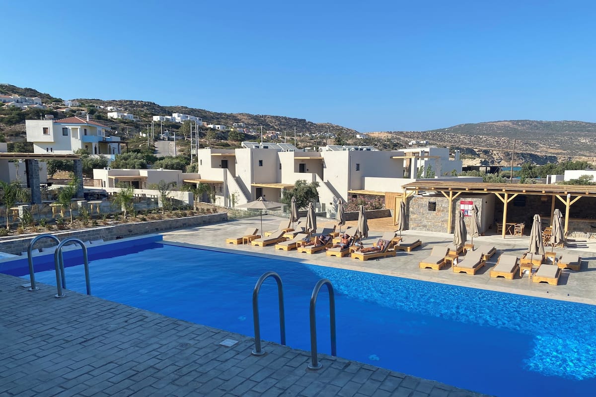 Piscina con tumbonas y vistas a edificios en la ladera.