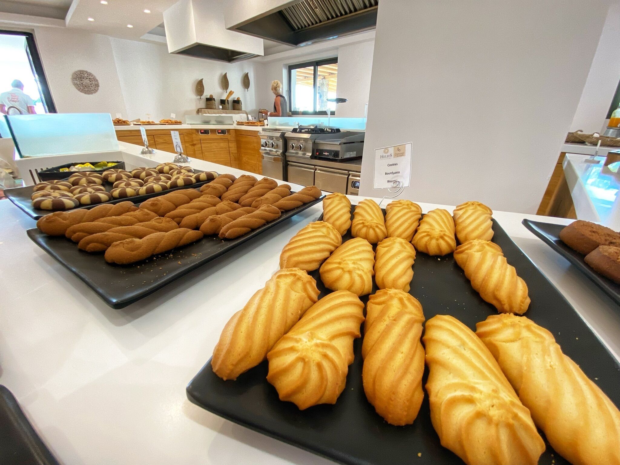A bakery display with various pastries and a kitchen in the background.