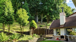 Een verzorgde tuin met een stenen muur, een houten omheining en een stenen schoorsteen.