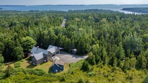 A large house surrounded by dense forest with a view of a lake. - Wonderland Home | 2BR retreat, mins to Acadia NP (Tremont)