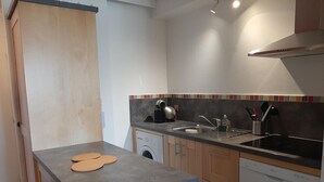 Une cuisine de taille réduite équipée d’un lave-linge, d’un évier et d’une cuisinière.